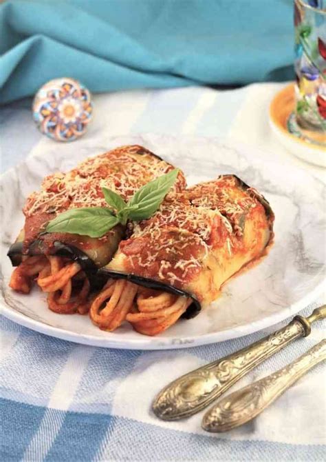 2 eggplant involtini with maccaruna on a white plate with utensils on