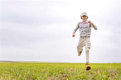young man running  camera  grassy field stock photo