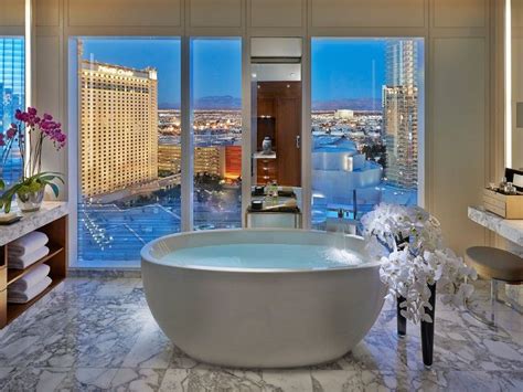 a large bath tub sitting in the middle of a bathroom next to a tall window