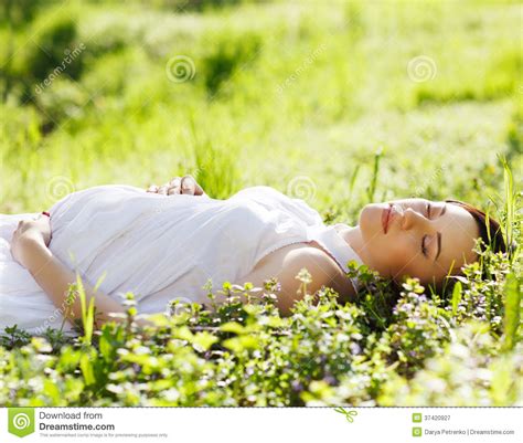 beautiful pregnant woman on grass in the spring park stock