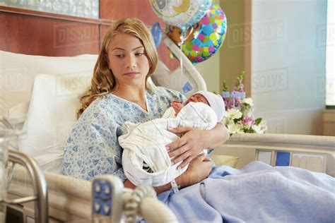 unhappy teenage girl holding newborn baby son  hospital stock photo