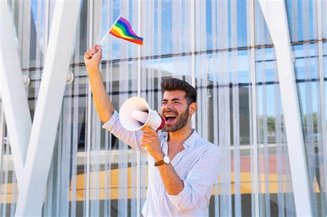 Side View Of Eccentric Gay Male With Rainbow Lgbt Flag Standing In City