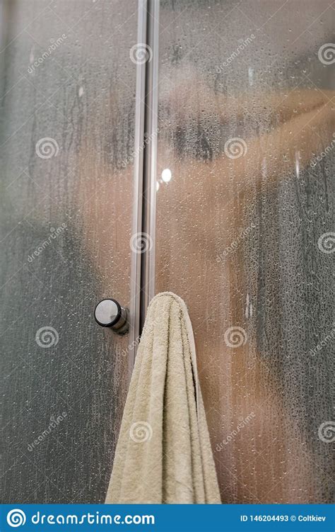 beautiful woman in the shower behind glass with drops woman in the