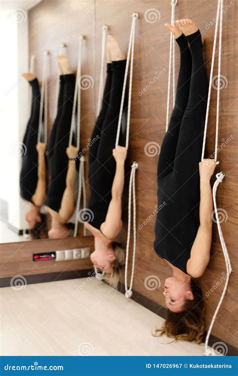 women hanging on ropes upside down practicing yoga on ropes stretching