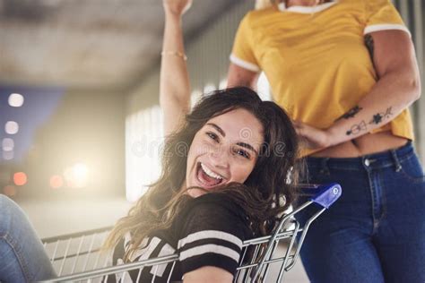 Laughing Girlfriends Pushing Each Other In A Shopping Cart Stock Image
