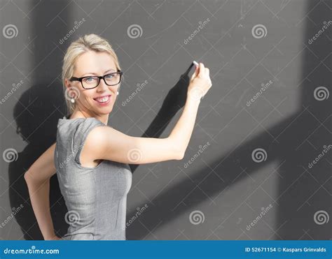 Smiling Teacher With Glasses Standing In Front Of Blackboard And