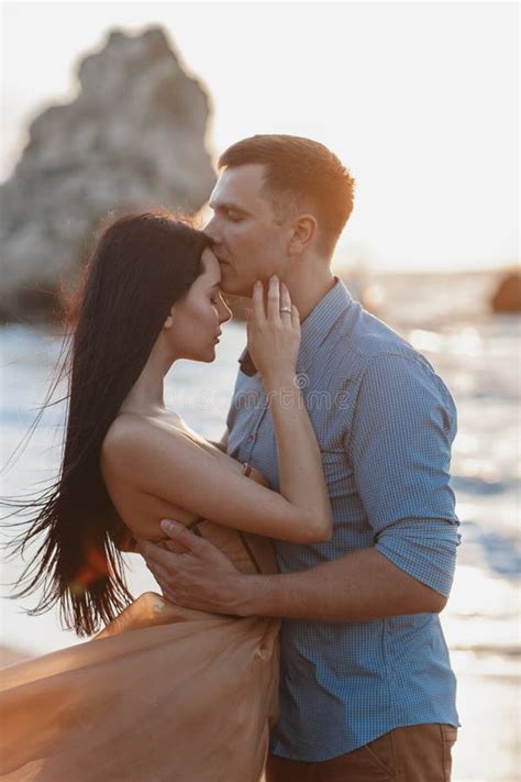 Happy Couple In Love During Honeymoon On A Rocky Beach Near The Blue