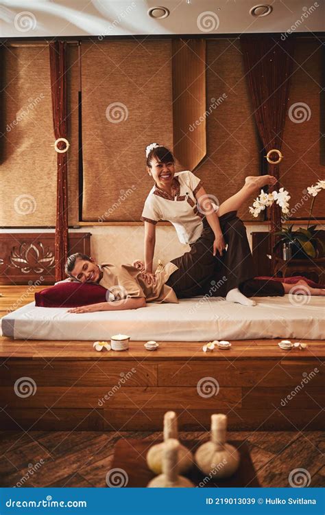 thai female spa worker  leg stretches  client stock image