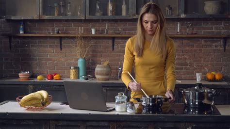 Woman Cooking And Use Laptop Looking On Screen Laptop Reading Recipe