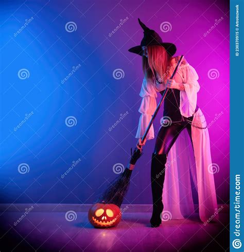 a girl in a witch costume for halloween with a broom and a pumpkin in
