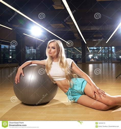 blonde woman in sports clothing posing with silver yoga