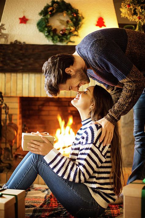 Romantic Couple With Christmas Present Rubbing Noses At Home Photograph