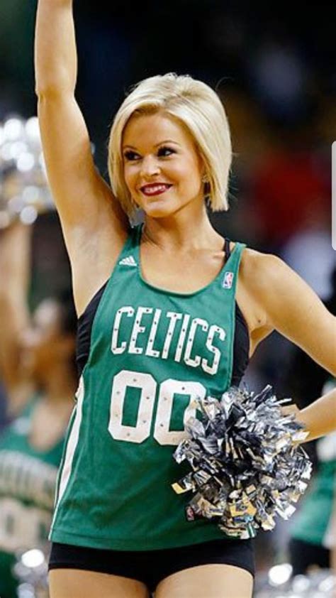 a cheerleader in green and black uniform with her hands up