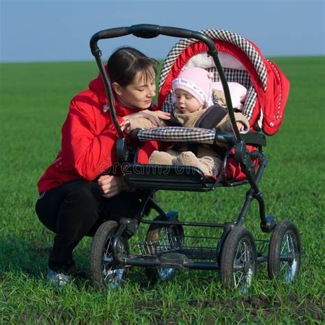Mujer Que Mira En El Carro De Bebé En Parque Imagen De