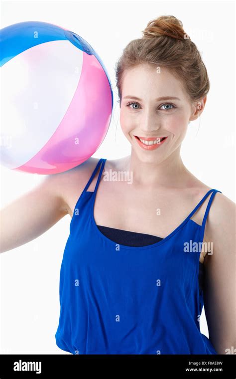 Smiling Woman In Blue Shirt Holding A Beach Ball On Her Shoulder Stock