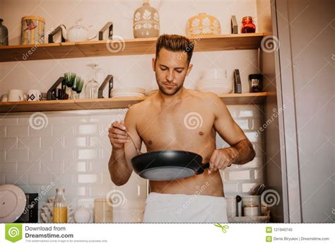 cuoco unico sexy con l ente nudo che cucina nella cucina