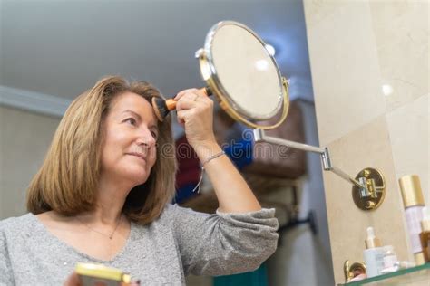 Mature White Woman Applying Beauty Treatments In Front Of The Mirror Of