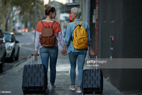 lesbian couple walking together with rolling suitcases photo getty images