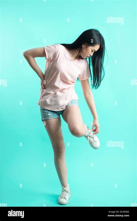 Asian Sporty Woman With Long Hair In Denim Shorts Adjusting Laces On