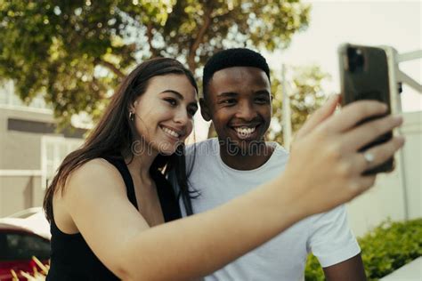 Biracial Couple Taking Selfies On The Phone At College Stock Image