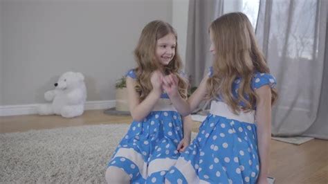 two positive caucasian twin sisters in elegant blue dotted dresses
