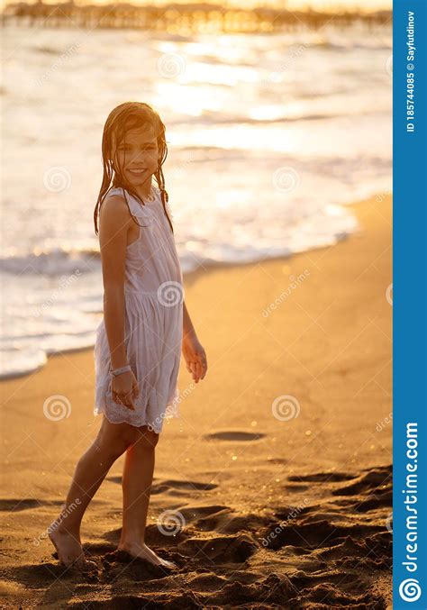 teen girl in wet dress standing on sandy shore swimming