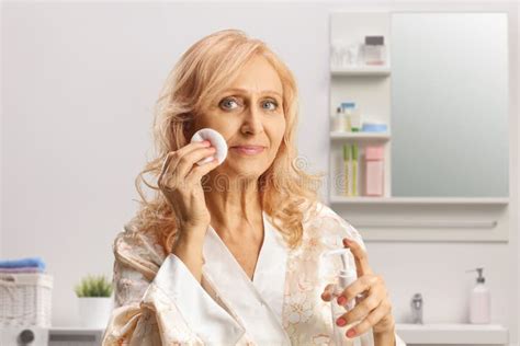 Mature Woman Cleaning Her Face With A Cotton Pad And Face Tonic In A