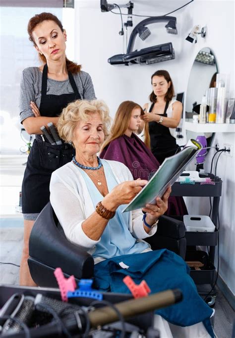 young woman hairdresser  hair salon helping  senior woman ch stock