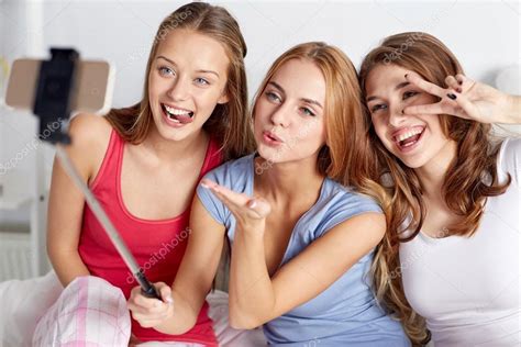 teen girls with smartphone taking selfie at home — stock