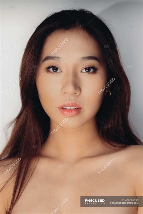 Portrait Of Naked Young Chinese Woman Looking At Camera Over White
