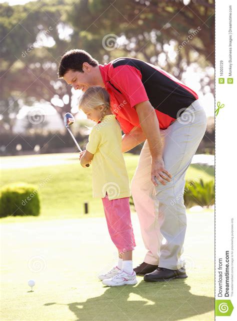 father teaching daughter to play golf royalty free stock
