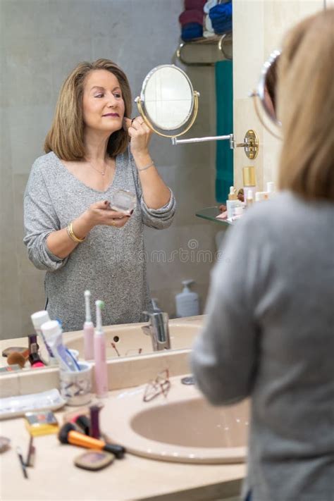 Mature White Woman Applying Beauty Treatments In Front Of The Mirror Of
