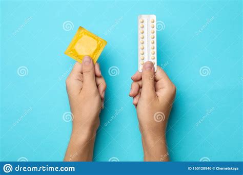 woman holding condom and birth control pills on blue background safe