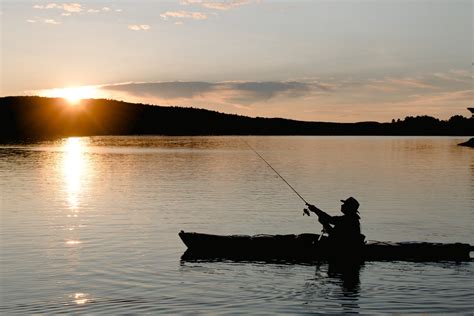 unrecognizable fisherman  boat fishing  lake  sunset  stock