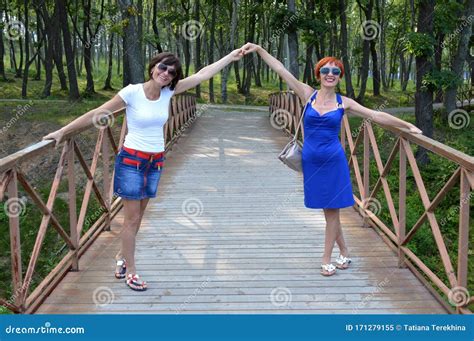 Two Russian Sisters Holding Hands And Sincerely Laughing With Natural