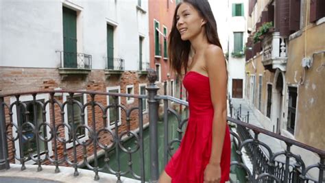 happy beautiful woman in red summer dress walking over canal bridge smiling in venice italy