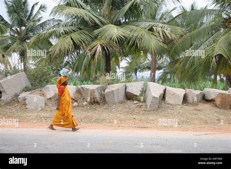 a indian woman walks down the street carrying her belongings on her