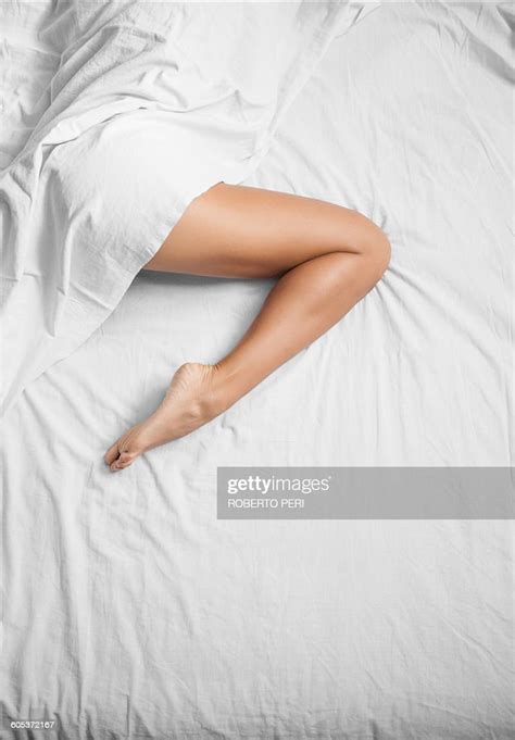 overhead view of white sheets and female bare leg on bed photo getty
