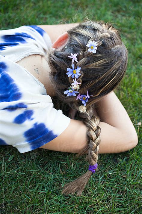 girl laying in the grass with a french braid and flowers in her hair by
