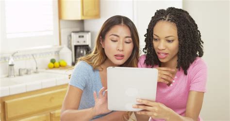 African American And Asian Women Friends Using Cell Phones