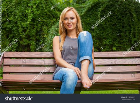 sensual blonde woman sitting in park on wooden bench outdoor photo she looks relaxed