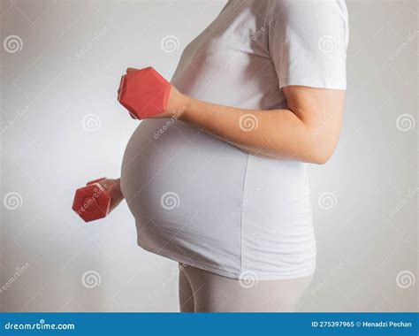pregnant girl with a big belly and dumbbells on a white background the