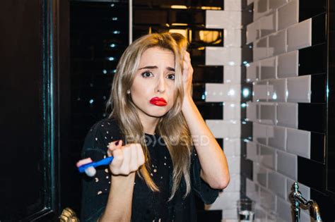 sad blonde woman posing with teeth brush at bathroom — healthy