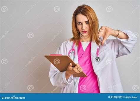 roodkopkaukasische doktersvrouw met roze stethoscoop en klembord met een negatief teken op een
