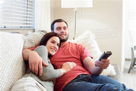 caucasian couple cuddling  sofa watching television stock photo