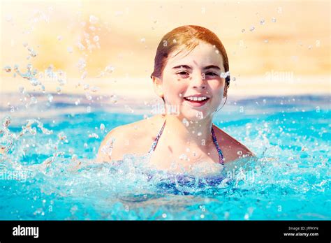 porträt eines lächelnden mädchens spielen im pool spritzwasser