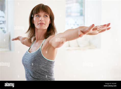 Portrait Of Mature Woman Stretching Her Arms And Looking Away At Gym