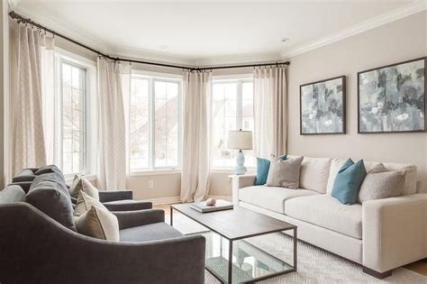 welcoming living room features bay windows dressed  cream curtains complementing cream colo