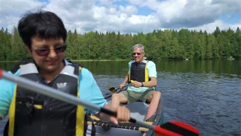 Mature Couple Canoeing On A Forest Lake In Finland Active