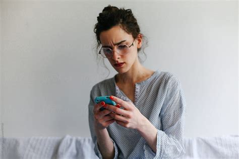Woman With Glasses Using Her Mobile Phone By Stocksy Contributor